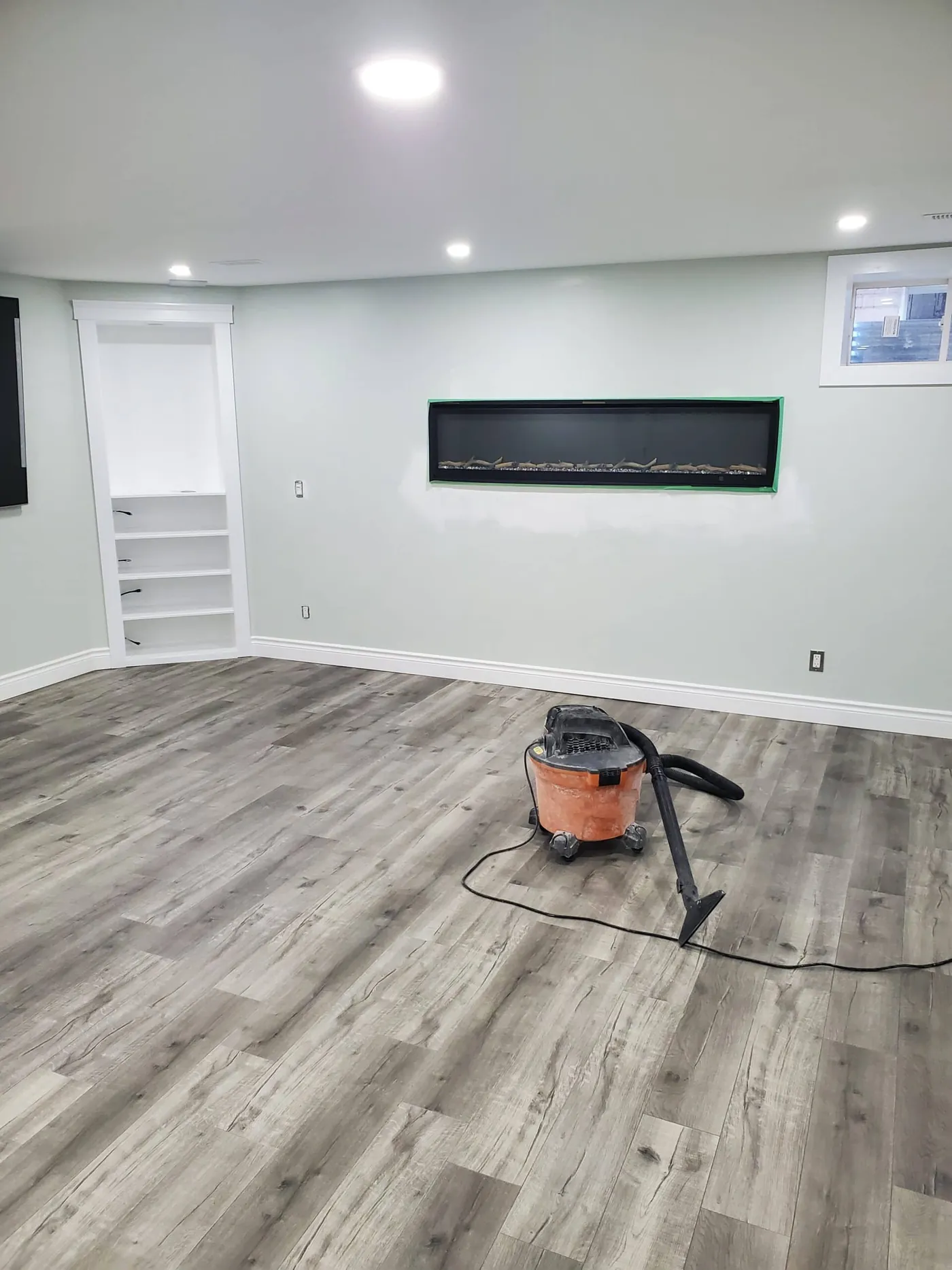 Lower-level family room with a linear fireplace and fresh white walls