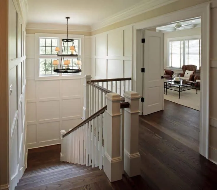 Bright foyer with painted wainscoting, white railings and a chandelier