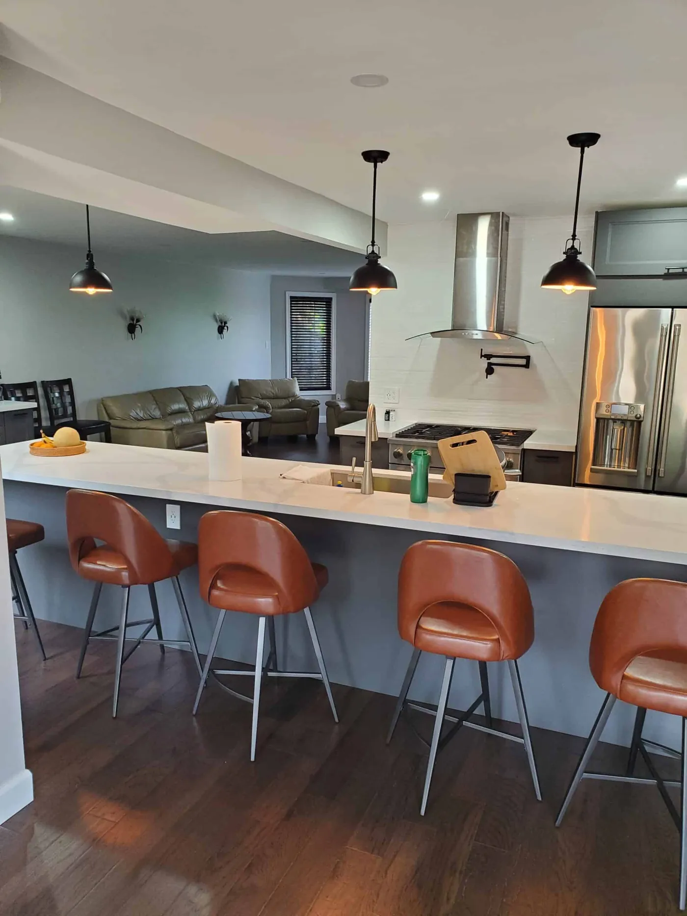 Finished kitchen with white cabinets, a dark painted island and pendant lights