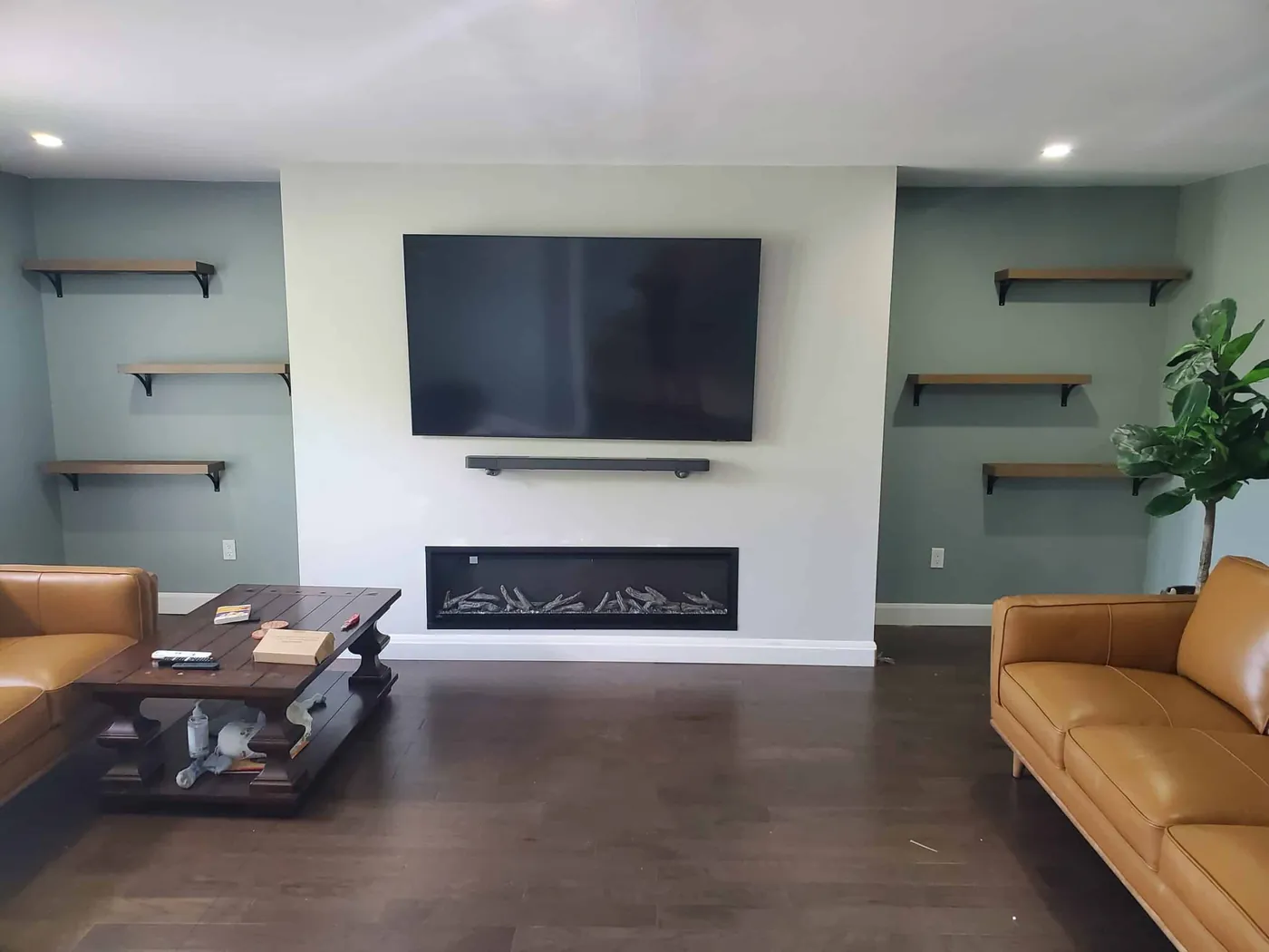Living room with a sage green feature wall, white trim and a linear fireplace